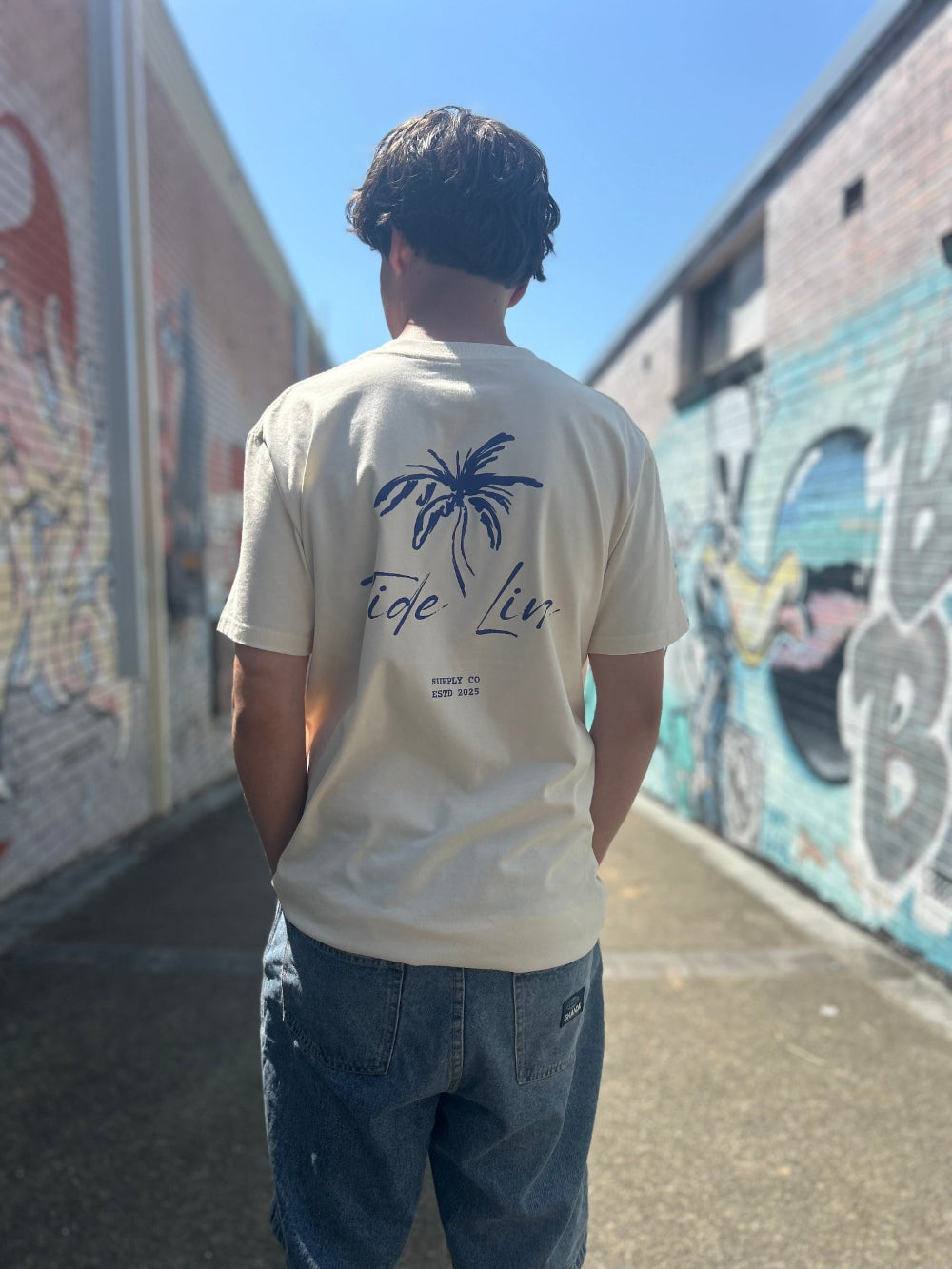 Male model wearing natural heavyweight palm print tee showing design back